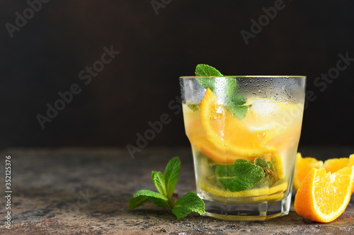 Summer drink. Cold lemonade with lemon, orange and mint on a concrete background. Horizontal focus.