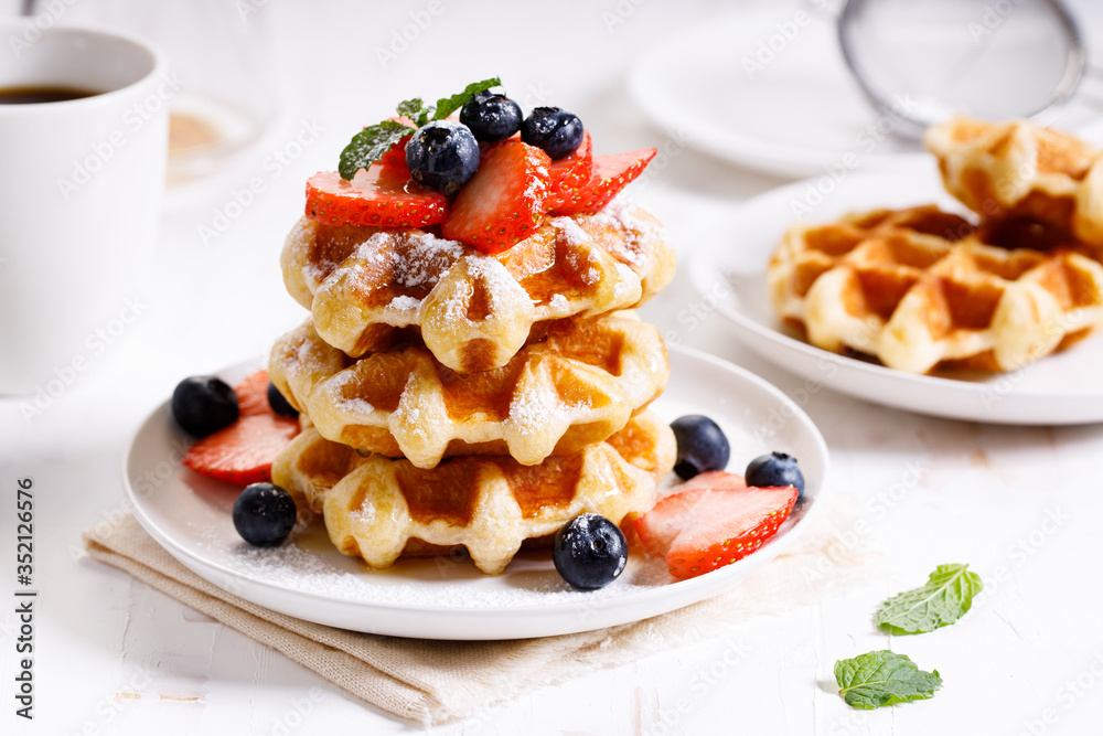 belgian waffles with fresh blueberries, strawberries and sugar. belgian waffles with fresh blueberries, strawberries and sugar.