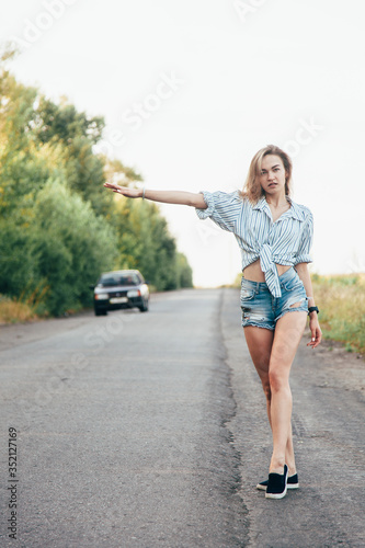 Beautiful girl hitchhiking on the track in a man's shirt