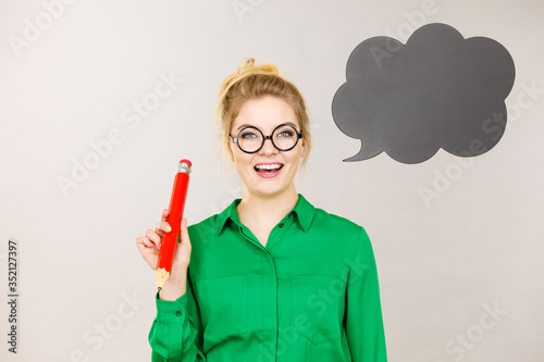 Woman holding big oversized pencil thinking