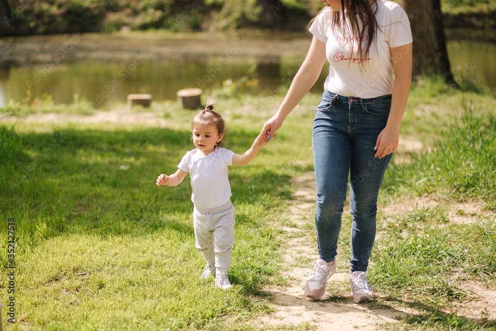 Fototapeta premium Cute little girl spend time with mom neae the house. Mother and daughter walk on the backyard