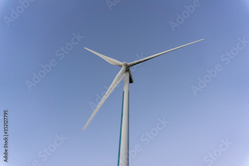White wind power turbines or windmill generators farm for producing electricity with renewable energy. It is the way to save environmental.