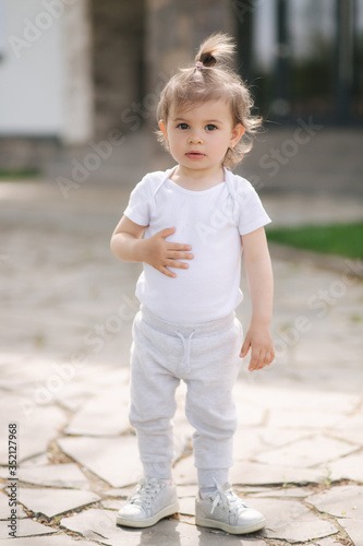 Adorable little girl walk near the house. Beautiful kid spend time in front of the house