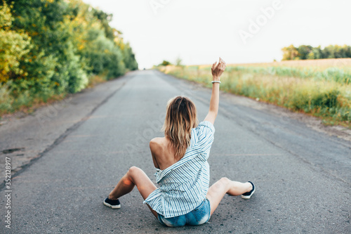 Beautiful girl hitchhiking on the track in a man's shirt