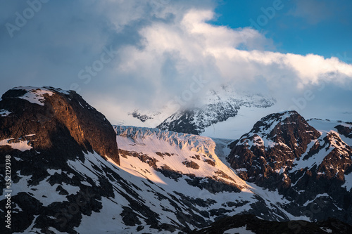 glacier in the swiss alps during the evening in warm light and with clouds and blue sky