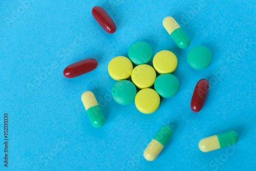 Many scattered colorful pills on blue background.
