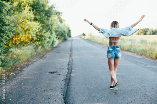 Beautiful girl hitchhiking on the track in a man s shirt