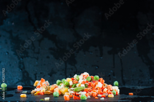 A mound of frozen vegetables in the center of the frame on a dark cold background