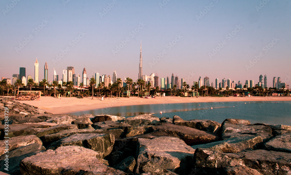 Dubai skyline, cityscape in the background. Beautiful beach scene and rocks in the foreground