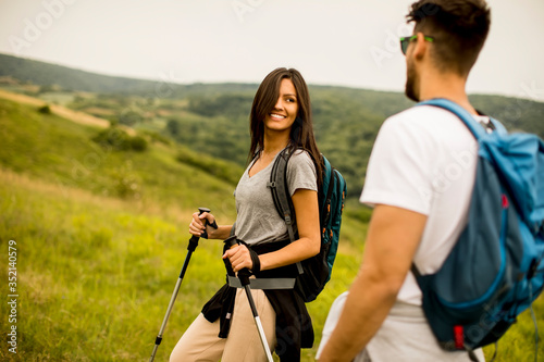 Smiling couple walking with backpacks over green hills