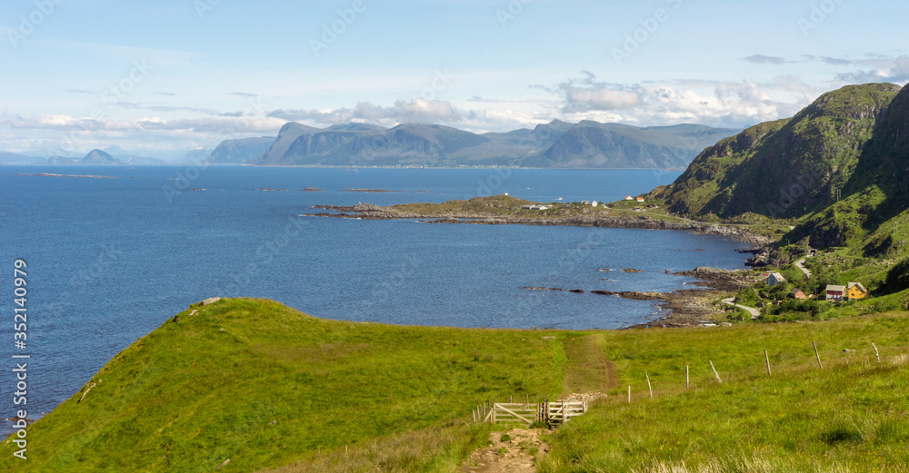 View from Runde bird island in Alesund, Norway towards little fishing village, the ocean and the mountains in the background.