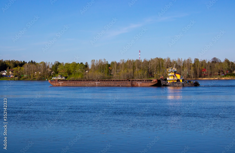 A tug pushing a heavy barge on the spring river.
