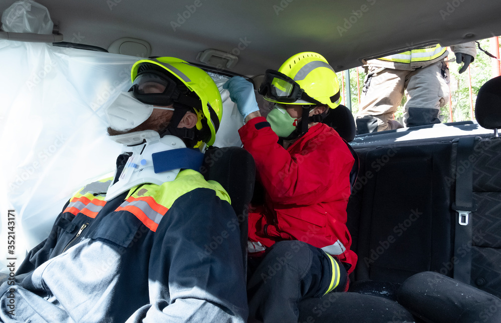 A sanitary wearing a mask places a collar on the injured person inside the injured vehicle. Protection by covid 19. Concept of rescue and rescue. A sanitary wearing a mask places a collar on the injured person inside the injured vehicle. Protection by covid 19. Concept of rescue and rescue.