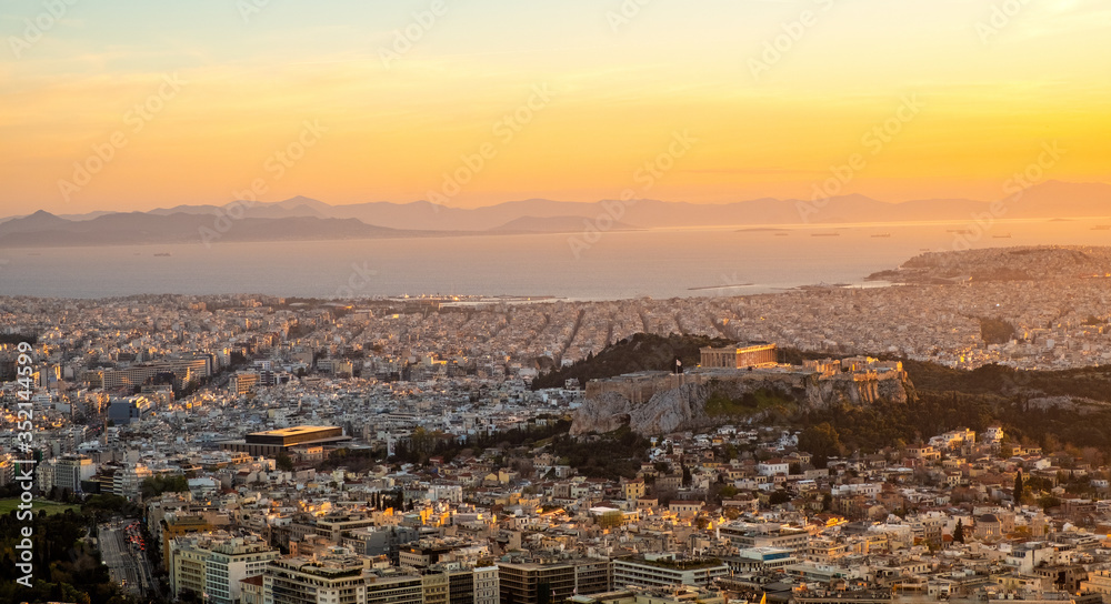 Panoramic sunset view of Athens, Greece, with Acropolis hill and Piraeus port at Saronic Gulf of Aegean sea in background seen from Lycabettus hill