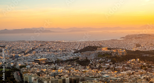 Panoramic sunset view of Athens, Greece, with Acropolis hill and Piraeus port at Saronic Gulf of Aegean sea in background seen from Lycabettus hill