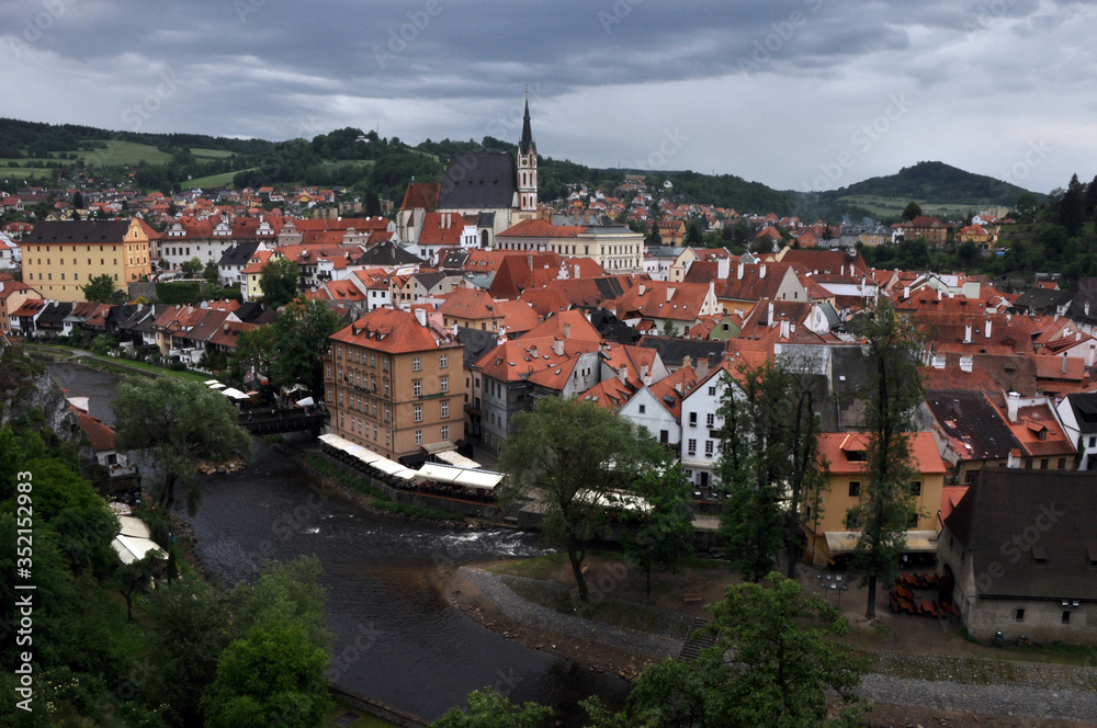 Panorama of tiled roofs of buildings of the historic part of Cesky Krumlov. View of the ancient bridge over the Vltava, the embankment and St. Vitus Church.