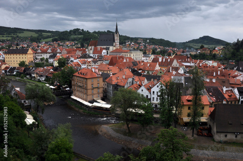 Panorama of tiled roofs of buildings of the historic part of Cesky Krumlov. View of the ancient bridge over the Vltava, the embankment and St. Vitus Church.