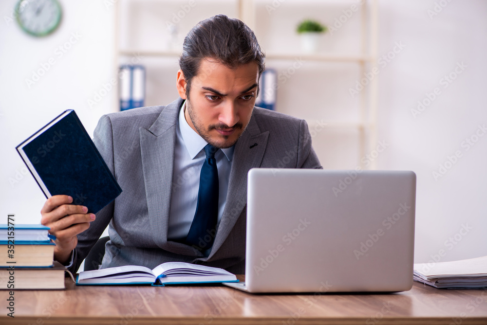 Young male businessman reading books at workplace Young male businessman reading books at workplace