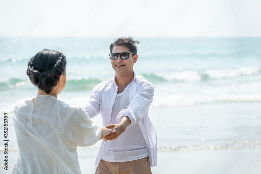 Smiling Asian senior couple holding hands together and looking at each other on tropical beach. Happy family retired old age man and woman relax and enjoy with romantic summer holiday vacation travel Smiling Asian senior couple holding hands together and looking at each other on tropical beach. Happy family retired old age man and woman relax and enjoy with romantic summer holiday vacation travel