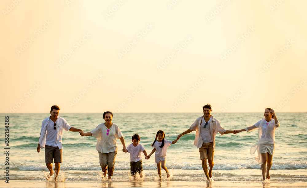 Group of Happy multi generation Asian family relax and having fun together on tropical beach in summertime. Smiling big family parents with child boy and girl enjoy in summer lifestyle travel vacation