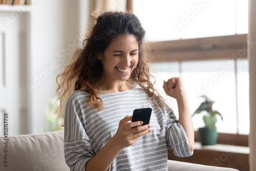 Satisfied woman reading good news in email or social network message close up, excited girl looking at phone screen, showing yes gesture with hands, celebrating success, online lottery win