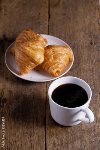 Fototapeta Naklejka Na Ścianę i Meble -  cup of hot coffee  with croissant on dark wooden background.  Working at home concept.