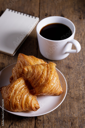 cup of hot coffee with croissant on dark wooden background. Working at home concept.
