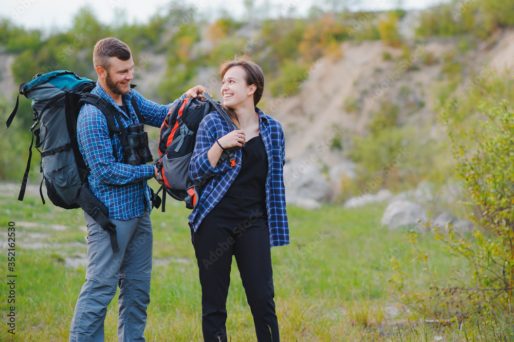 Couple enjoying beautiful views on the mountains, while traveling with backpacks in the mountains during the summer vacations Couple enjoying beautiful views on the mountains, while traveling with backpacks in the mountains during the summer vacations