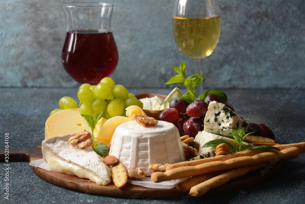 Cheese platter with assorted cheeses, grapes, nuts and snacks . Italian, French cheese starter. Traditional Shavuot Jewish Holiday food concept
