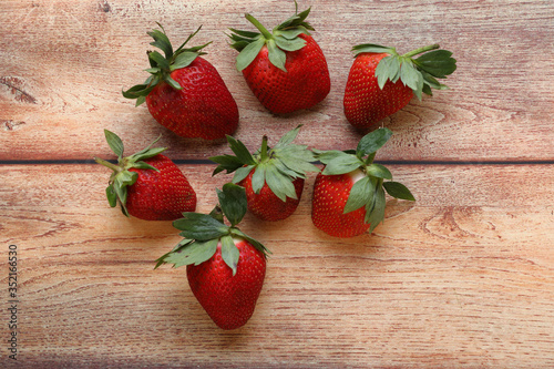 Various strawberries on wooden table seen from above