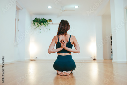 Yoga girl on her back and kneeling practicing the Anjali mudra pose