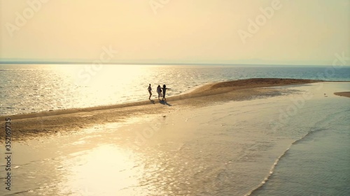 Three people walking on the beach during sunset. Saudi Arabia 