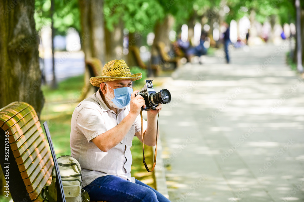old man relax in park. life during coronavirus lockdown. enjoy the beauty. fear of illness. photographer with camera on bench. prohibition on visiting public places. senior man in medical mask old man relax in park. life during coronavirus lockdown. enjoy the beauty. fear of illness. photographer with camera on bench. prohibition on visiting public places. senior man in medical mask