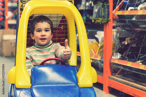 The boy is 4 years old in a construction shopThe boy is 4 years old in a construction shop, sitting in a cart. toned photo