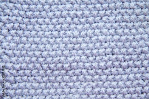 Background of textured knitted fabric in gray. Knitting with needles. Wool.