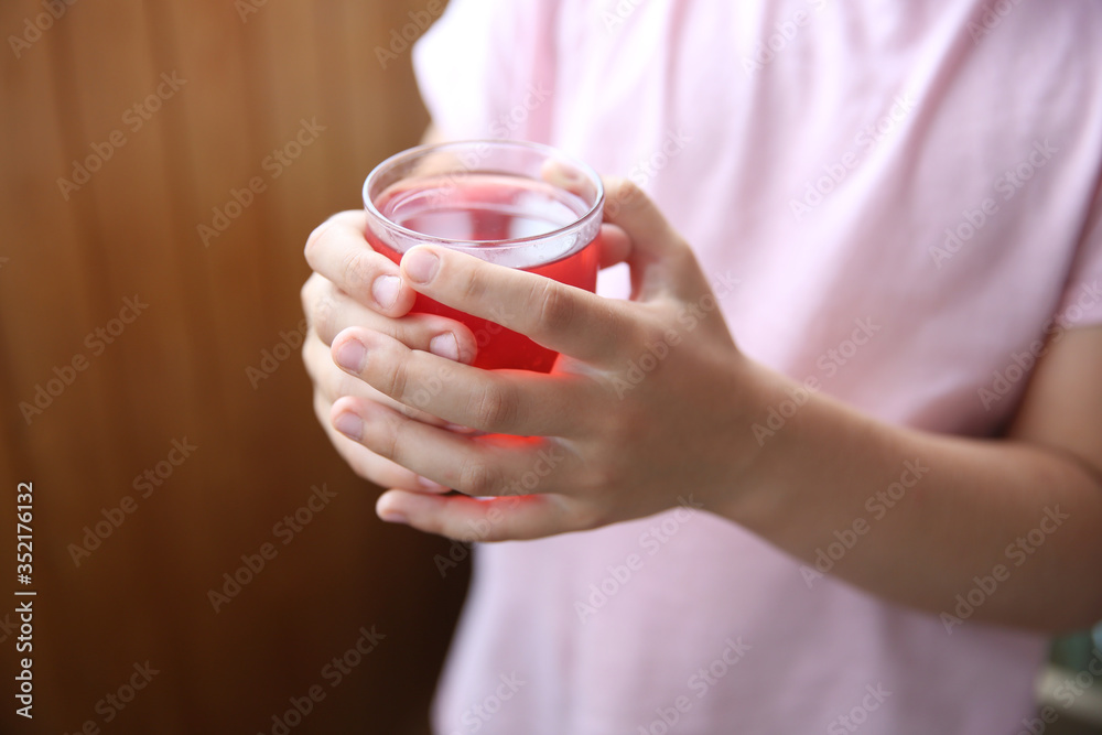 red drink or juice in the hands of a young girl in pink clothes on a brown background. red drink or juice in the hands of a young girl in pink clothes on a brown background.