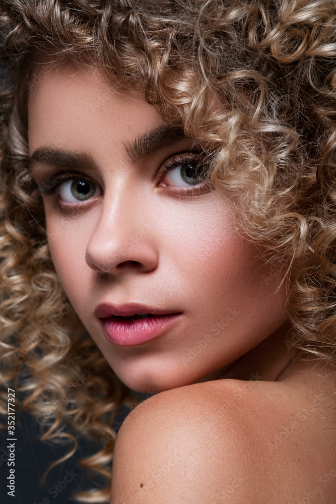 Fototapeta premium Cute cheerful woman close up portrait with afro curly hairstyle on a black background. Fresh, flawless skin