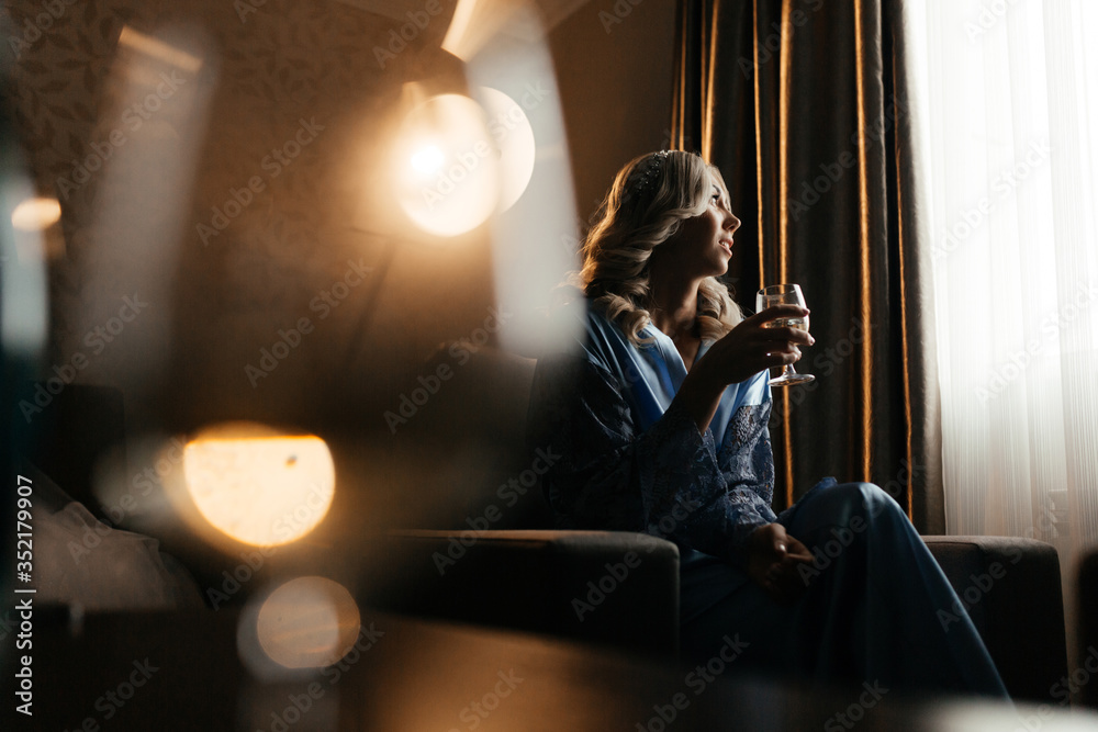 Blonde woman in the blue peignoir sitting in front of the window Blonde woman in the blue peignoir sitting in front of the window