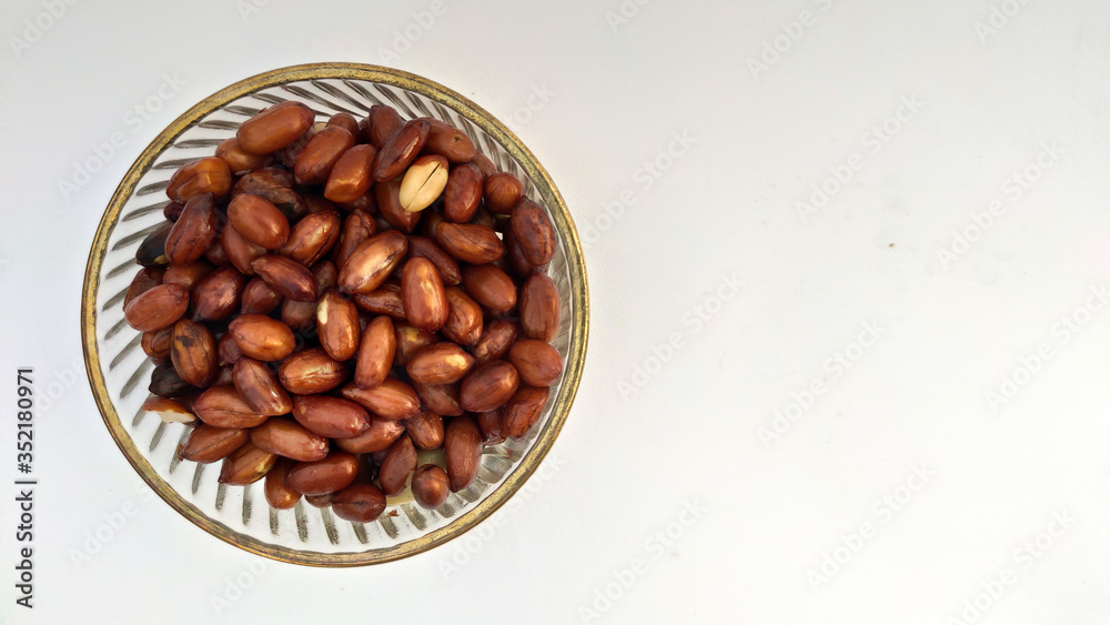 Fototapeta premium Top view of Roasted peanuts in glass bowl, Isolated on white background. 