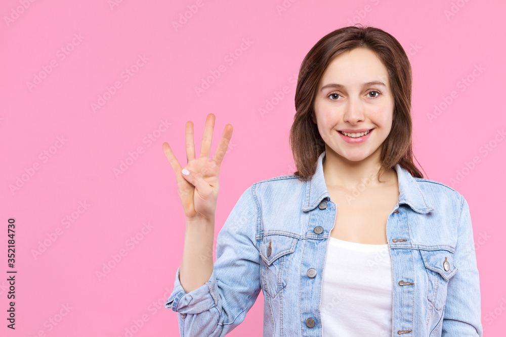 Cheerful smiling girl dressed in white t-shirt, denim jacket on pink background. Young woman is showing with fingers number four, percents, discount. Female gesturing. Emotional portrait concept. Cheerful smiling girl dressed in white t-shirt, denim jacket on pink background. Young woman is showing with fingers number four, percents, discount. Female gesturing. Emotional portrait concept.