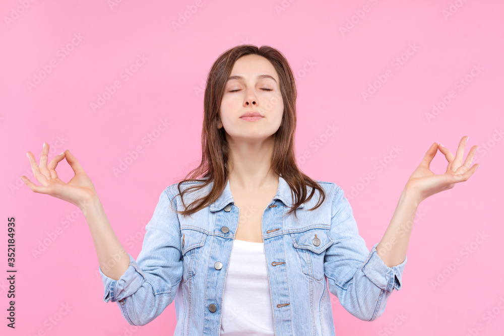 Pretty smiling girl dressed in white t-shirt, denim jacket on pink background. Young woman is relaxing, meditating, practicing yoga, keeping calm. Female gesturing. Emotional portrait concept. Pretty smiling girl dressed in white t-shirt, denim jacket on pink background. Young woman is relaxing, meditating, practicing yoga, keeping calm. Female gesturing. Emotional portrait concept.