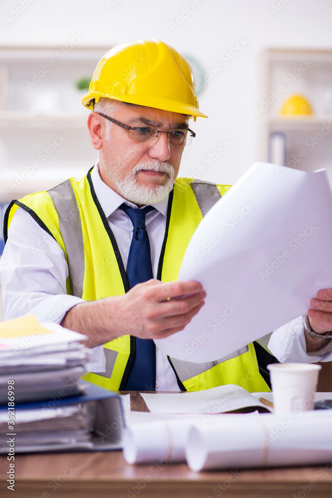 Old male architect working in the office