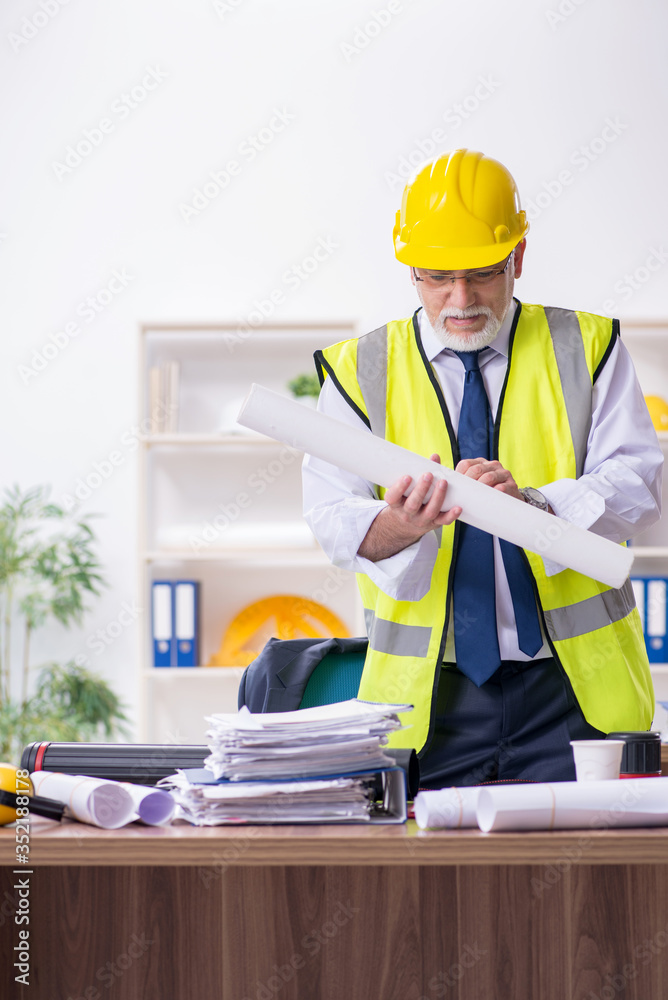 Old male architect working in the office Old male architect working in the office