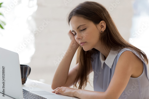 Tired woman worker fall asleep at workplace overwhelmed with computer work  unwell millennial female take nap sleep exhausted from studying or working on laptop  fatigue  overwork concept