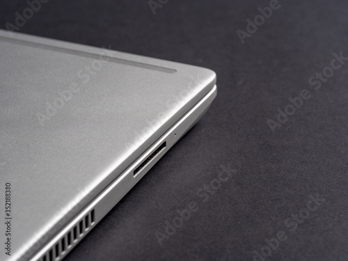 Side view of a silver closed laptop on a dark paper background