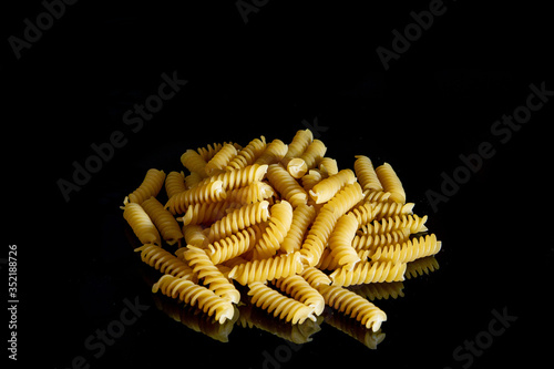 Fusilli pasta over black background. Cooking concept. Top view with copy space.