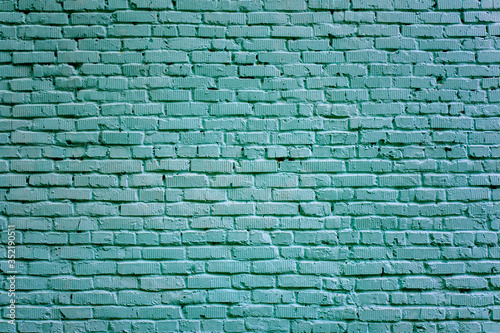 Fragment of an old brickwork closeup. The wall of bricks is painted. Potholes and defects of a brick wall.