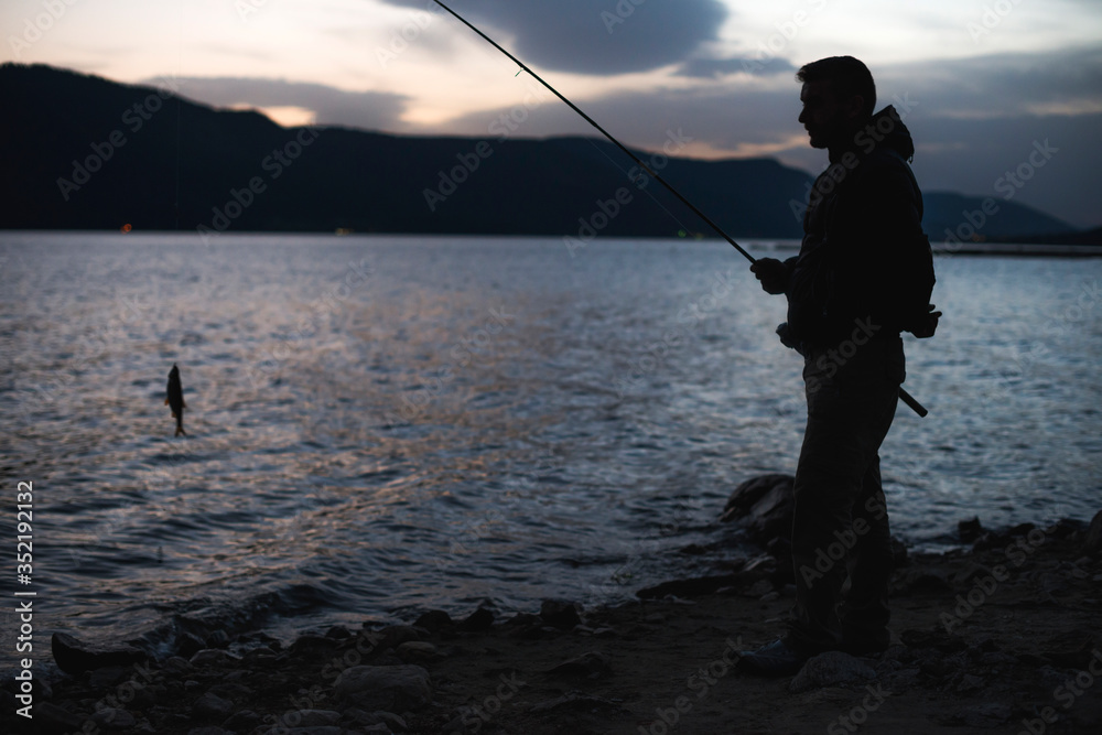Man fishing on mountain lake. Sunrise low light. Man fishing on mountain lake. Sunrise low light.
