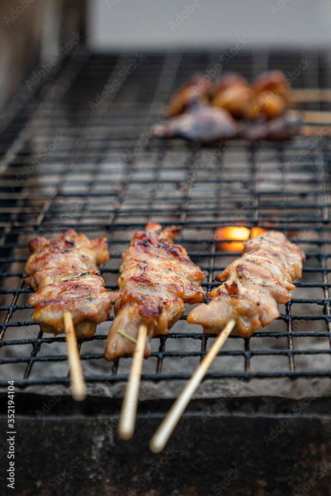 Thai street food-kebabs on the grill. fried pieces of pork on the coals. vertical close-up photo. outdoor