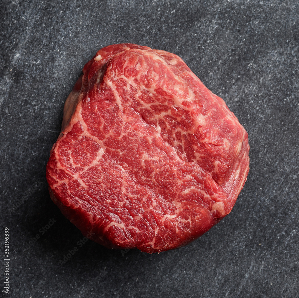 Raw beef fillet steak on black background top view